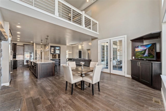 dining room featuring dark hardwood / wood-style flooring, sink, french doors, and a high ceiling