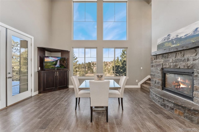 dining room with hardwood / wood-style floors, a towering ceiling, and a fireplace