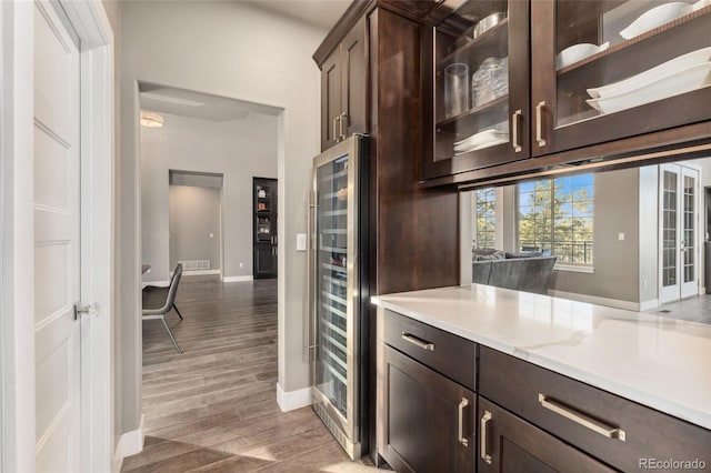 kitchen with hardwood / wood-style flooring, dark brown cabinets, and wine cooler