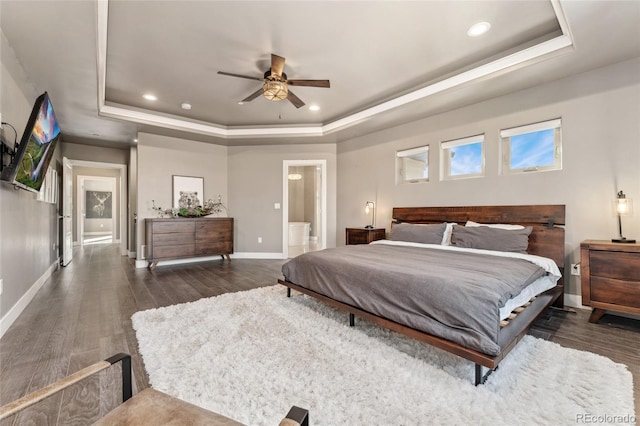 bedroom with dark hardwood / wood-style floors, a raised ceiling, and ensuite bathroom