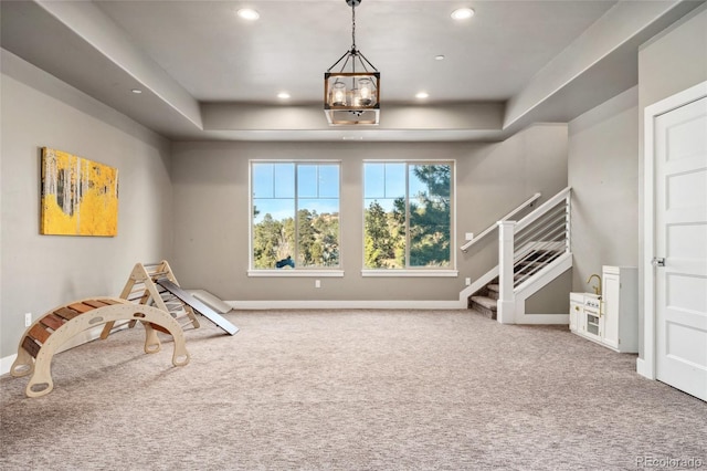 recreation room with carpet floors and a tray ceiling