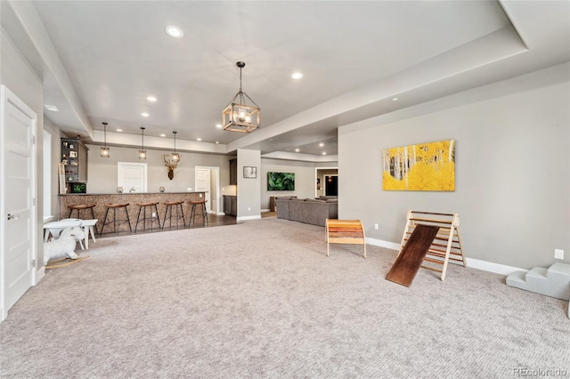 interior space featuring carpet flooring, an inviting chandelier, and a tray ceiling