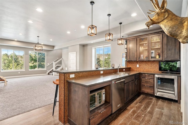 kitchen featuring sink, a breakfast bar area, dishwasher, kitchen peninsula, and beverage cooler