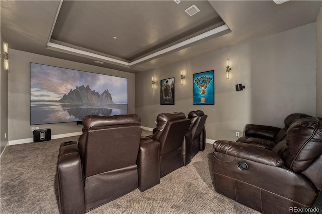 home theater room featuring a tray ceiling and carpet