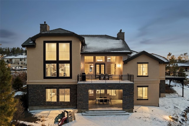 snow covered rear of property with a patio and a balcony