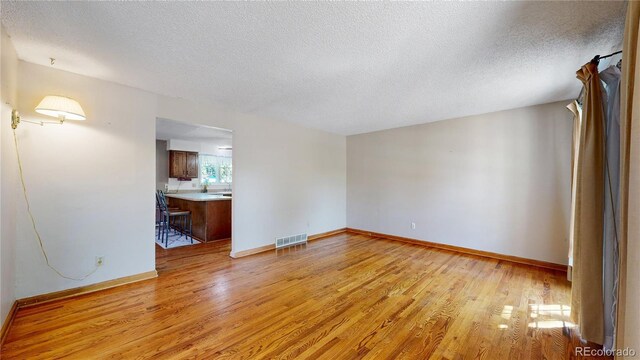 unfurnished room with light wood-type flooring and a textured ceiling