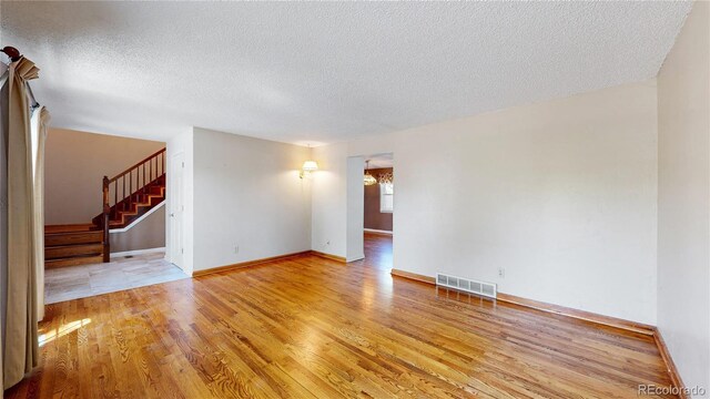 spare room featuring a textured ceiling and light hardwood / wood-style flooring