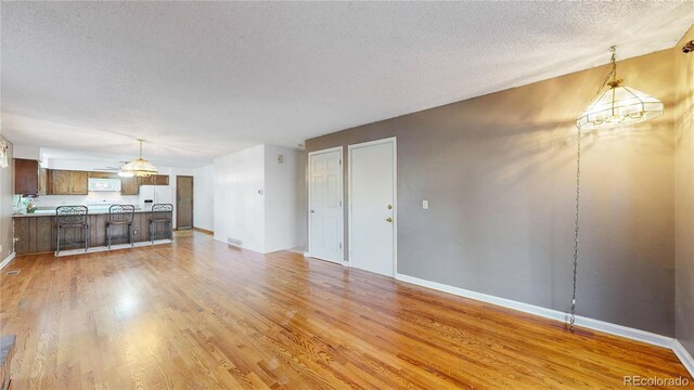 unfurnished living room featuring ceiling fan, a textured ceiling, and light hardwood / wood-style flooring