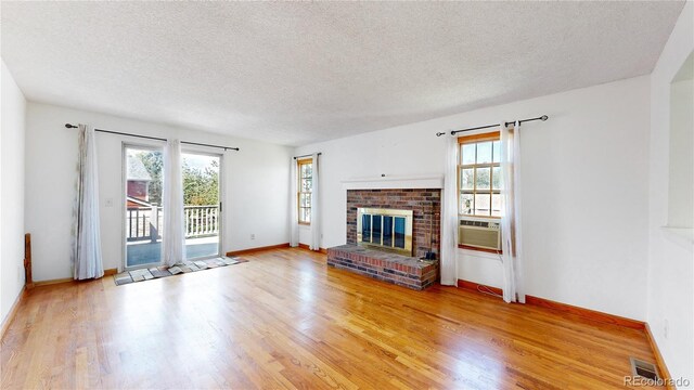 unfurnished living room featuring a wealth of natural light, light wood-type flooring, and a fireplace