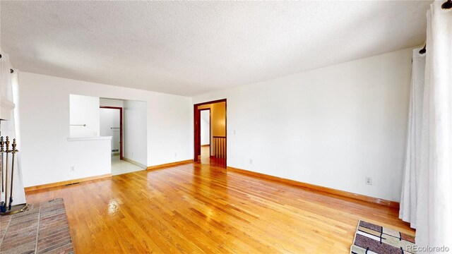 unfurnished living room featuring a textured ceiling and light hardwood / wood-style floors