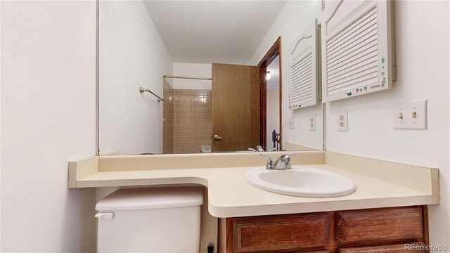 bathroom with vanity, toilet, and a tile shower