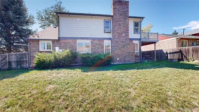 back of property featuring a balcony and a lawn