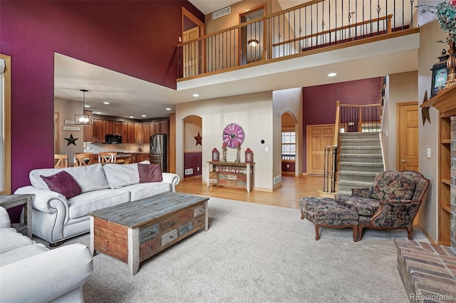 5683 Fig Way, Arvada, CO 80002 - living area featuring arched walkways, a towering ceiling, light carpet, stairs, and recessed lighting