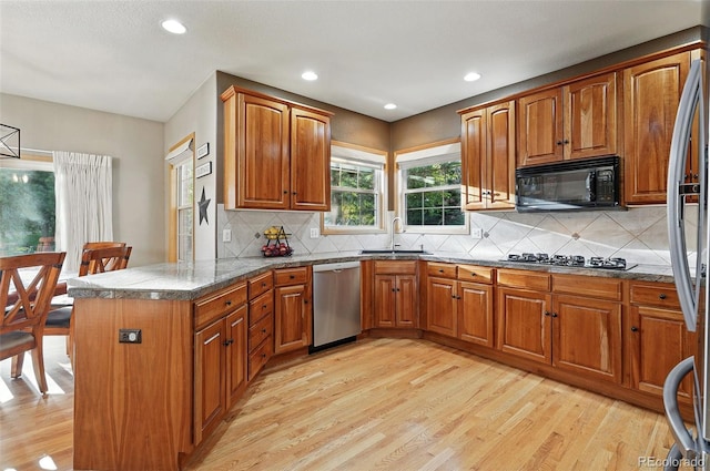5683 Fig Way, Arvada, CO 80002 - kitchen with stainless steel appliances, a sink, brown cabinets, light wood-type flooring, and a peninsula