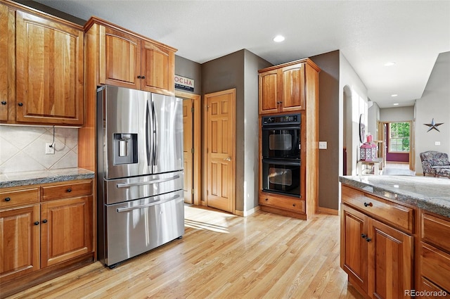 5683 Fig Way, Arvada, CO 80002 - kitchen with stainless steel refrigerator with ice dispenser, light wood-style flooring, brown cabinets, decorative backsplash, and tile countertops