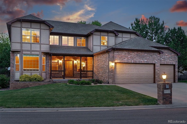 5683 Fig Way, Arvada, CO 80002 - tudor-style house with an attached garage, concrete driveway, a porch, a lawn, and stucco siding