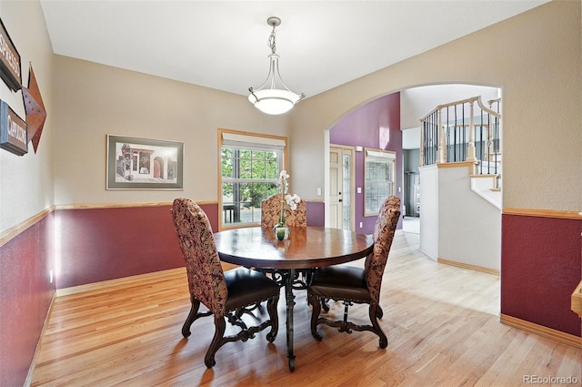 5683 Fig Way, Arvada, CO 80002 - dining room featuring arched walkways, light wood finished floors, stairs, and a textured wall