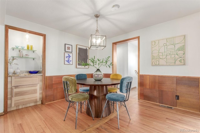 dining room with light wood-type flooring, visible vents, a chandelier, and wainscoting