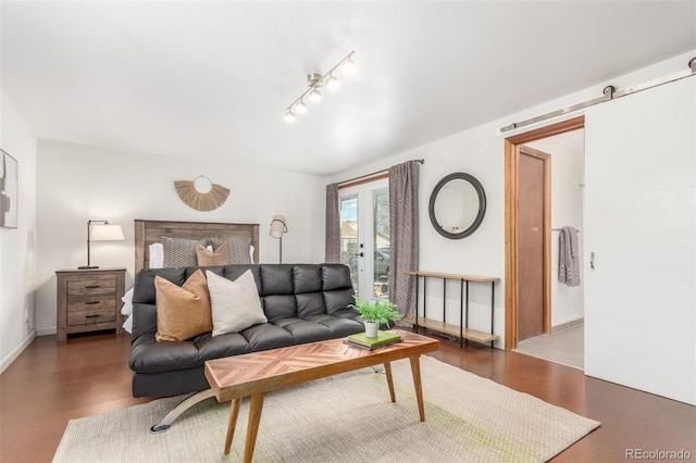 living area featuring a barn door, baseboards, and wood finished floors