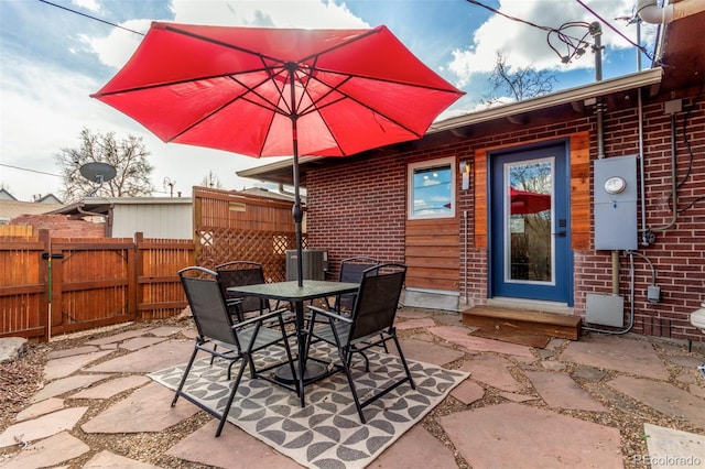 view of patio featuring outdoor dining area, entry steps, central AC unit, and fence