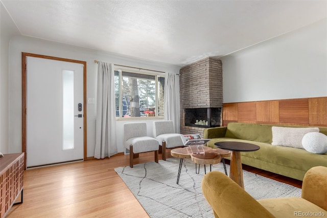 living area featuring light wood-style floors and a brick fireplace