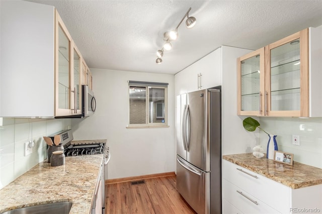 kitchen featuring baseboards, light wood-style flooring, white cabinetry, visible vents, and stainless steel appliances