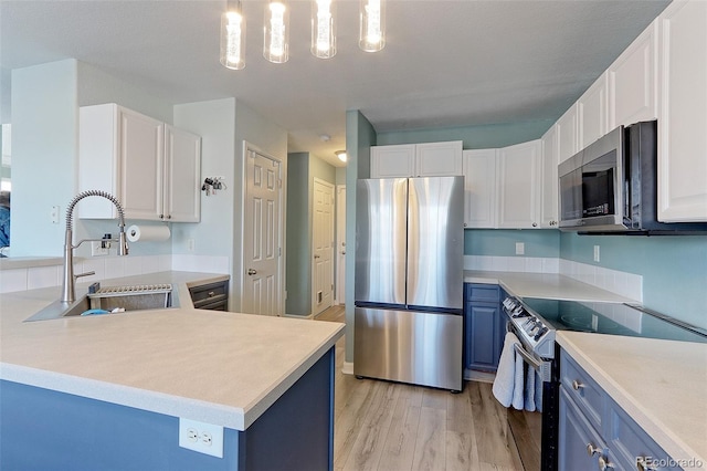 kitchen featuring pendant lighting, appliances with stainless steel finishes, a sink, and white cabinets