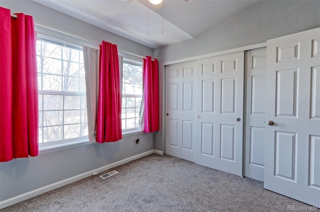 unfurnished bedroom with carpet flooring, visible vents, baseboards, vaulted ceiling, and a closet