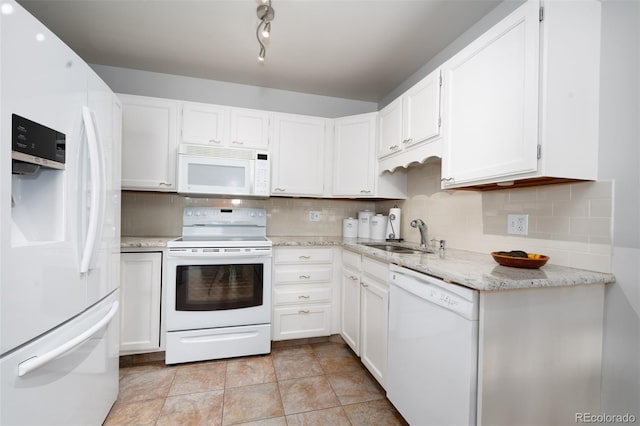 kitchen with white appliances, a sink, white cabinetry, decorative backsplash, and light stone countertops