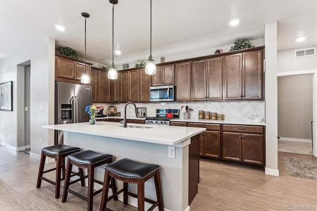 2012 Sagerock Dr, Castle Pines, CO 80108 - kitchen with stainless steel appliances, tasteful backsplash, a breakfast bar area, hanging light fixtures, and a kitchen island with sink