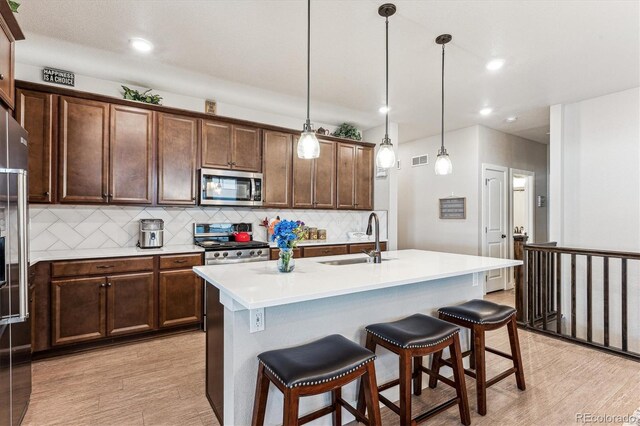 2012 Sagerock Dr, Castle Pines, CO 80108 - kitchen featuring appliances with stainless steel finishes, backsplash, a breakfast bar, light countertops, and pendant lighting