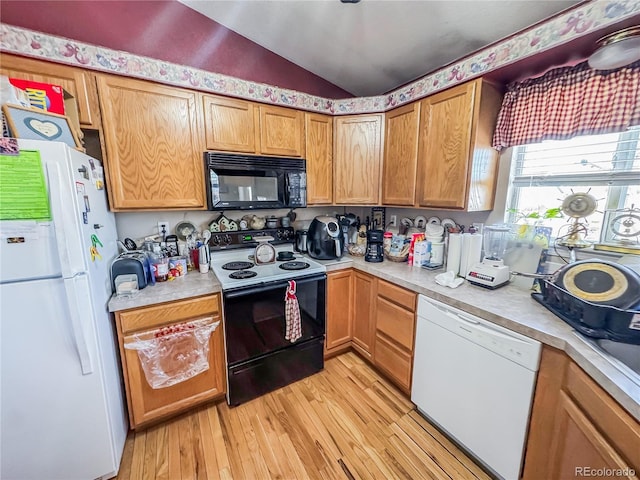 kitchen with vaulted ceiling, black appliances, and light wood-type flooring