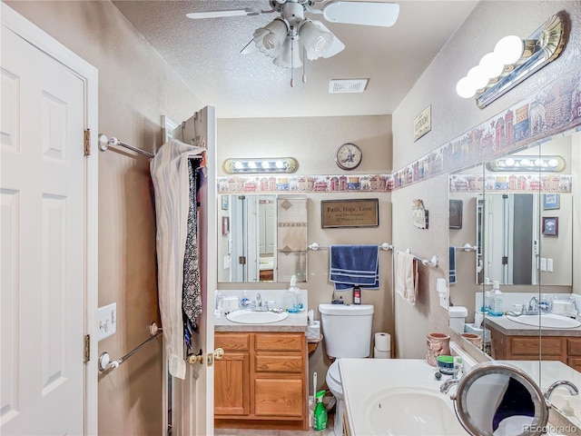 bathroom featuring ceiling fan, vanity, toilet, and a textured ceiling