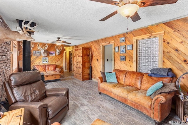 11679 US Highway 50, Howard, CO 81233 - living area featuring ceiling fan, a textured ceiling, wooden walls, a wood stove, and wood finished floors