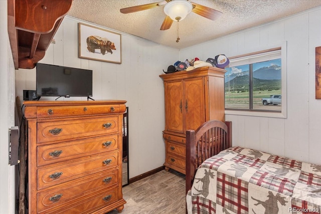 11679 US Highway 50, Howard, CO 81233 - bedroom featuring a textured ceiling, light wood-style flooring, a mountain view, wooden walls, and ceiling fan