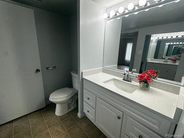 bathroom with a textured ceiling, vanity, toilet, and tile patterned floors