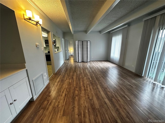 interior space featuring a textured ceiling, dark hardwood / wood-style floors, and beam ceiling