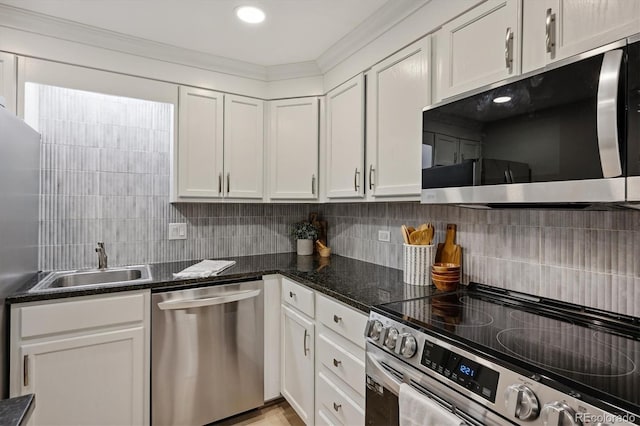 kitchen featuring appliances with stainless steel finishes, white cabinets, decorative backsplash, sink, and dark stone countertops