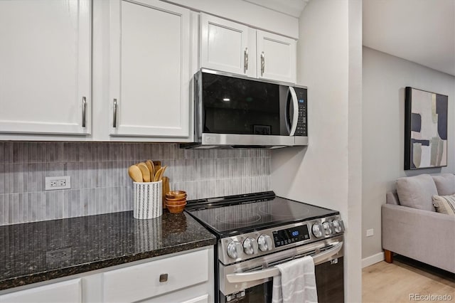 kitchen featuring white cabinets, stainless steel appliances, dark stone counters, and decorative backsplash