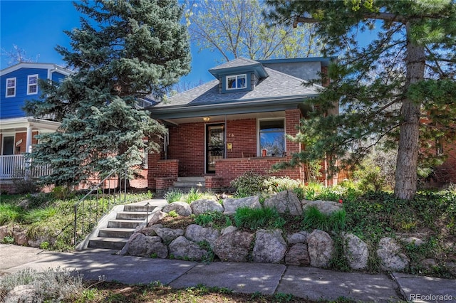 view of front of house featuring brick siding, a shingled roof, and covered porch