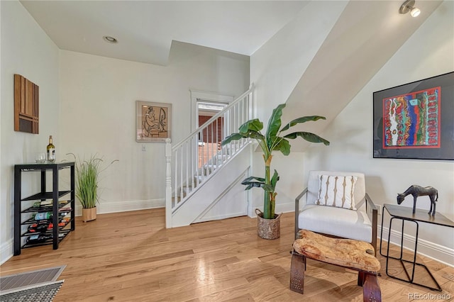 sitting room with stairs, baseboards, and wood finished floors
