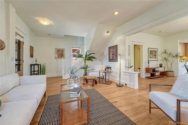 living area with recessed lighting, baseboards, light wood-style flooring, and stairway