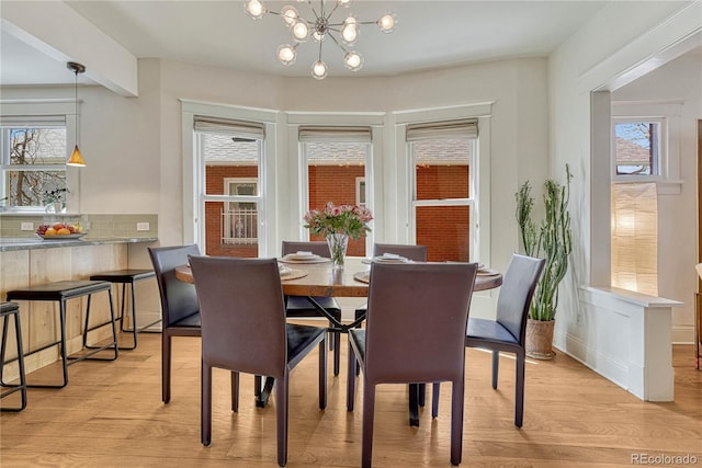 dining room with an inviting chandelier, plenty of natural light, and light wood finished floors