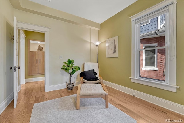 living area featuring baseboards and light wood finished floors