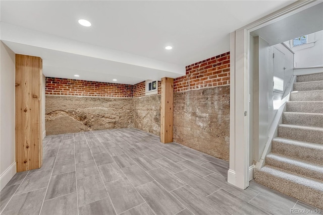 basement with recessed lighting, brick wall, and stairway
