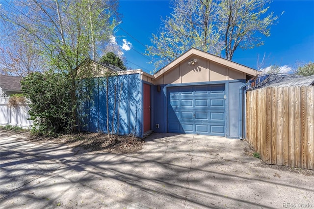 garage featuring fence and driveway