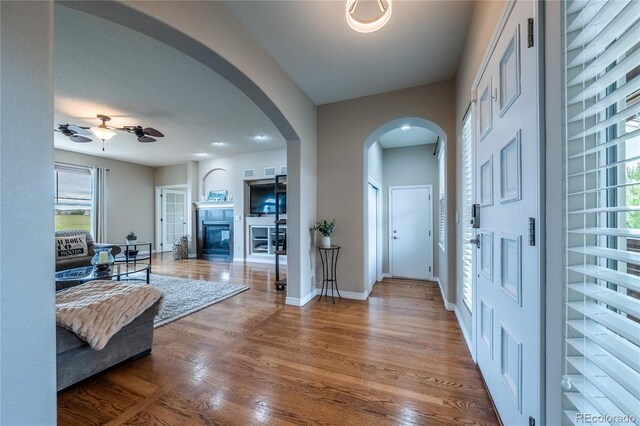 26741 E Arbor Dr, Aurora, CO 80016 - foyer entrance with arched walkways, wood finished floors, ceiling fan, baseboards, and a glass covered fireplace
