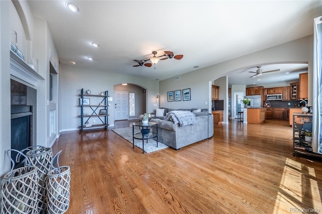 26741 E Arbor Dr, Aurora, CO 80016 - living room featuring a ceiling fan, arched walkways, a tile fireplace, wood finished floors, and recessed lighting