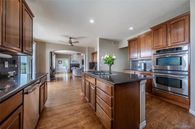 26741 E Arbor Dr, Aurora, CO 80016 - kitchen featuring appliances with stainless steel finishes, arched walkways, light wood-style floors, a ceiling fan, and decorative backsplash