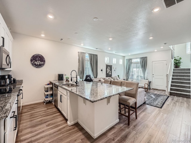 17991 E 103rd Ave, Commerce City, CO 80022 - kitchen with stainless steel appliances, a sink, a breakfast bar, light wood-style flooring, and recessed lighting